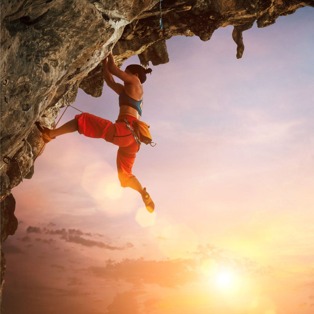 woman rock climbing outdoors at sunset