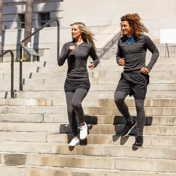 A man and Woman running down stairs in merino wool clothing