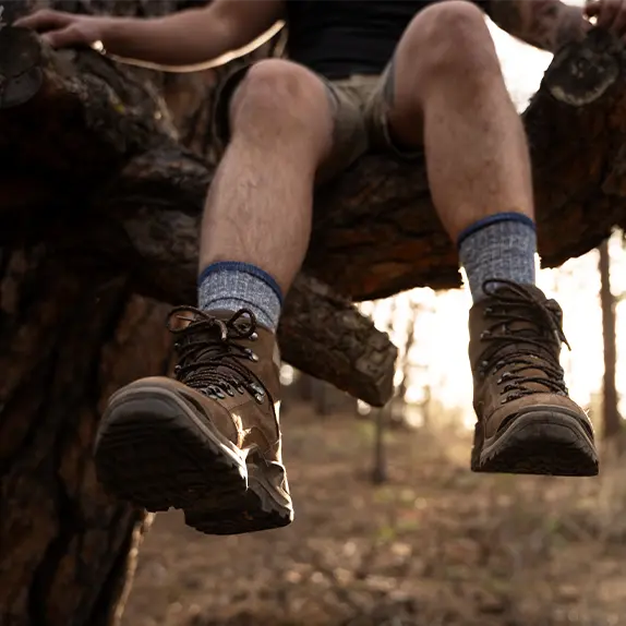 Foot swinging down from a tree branch with blue merino wool socks