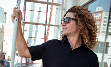 curly long hair man wearing black merino wool polo shirt